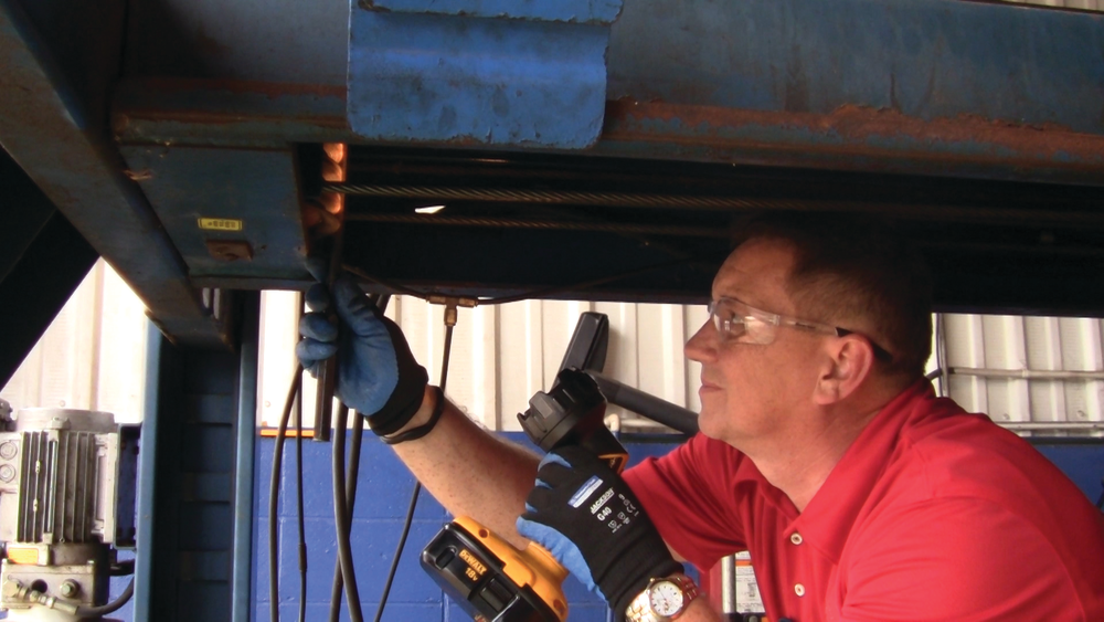 A lift inspector does an inspection on a four-post lift.