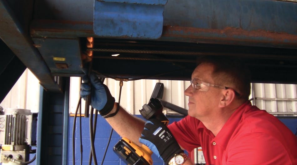 A lift inspector does an inspection on a four-post lift.