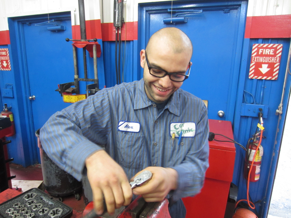 Alex Portillo repairing damaged threads on a strut from a 1996 Nissan Maxima.