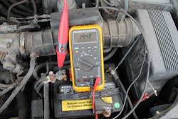 A technician checks the voltage while the vehicle is running, to confirm the charging system (alternator) is working correctly. A technician checks the voltage while the vehicle is running, to confirm the charging system (alternator) is working correctly.