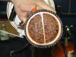 As sludge builds up in diesel fuel, bits of it slough off and travel downstream where they adhere to surfaces – like the bottom of this fuel filter – and start to grow new sludge. As sludge builds up in diesel fuel, bits of it slough off and travel downstream where they adhere to surfaces – like the bottom of this fuel filter – and start to grow new sludge.