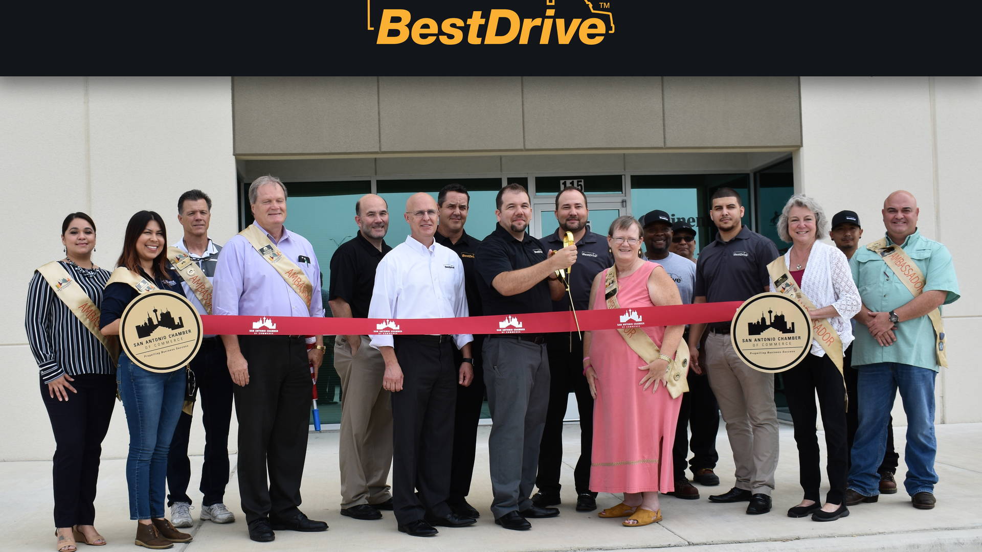 BestDrive San Antonio Operations Manager David Bunker cuts the ribbon. To his left are San Antonio Chamber of Commerce staff members, BestDrive Regional Manager Al Laicer, BestDrive Managing Director Sonny Simpson, and BestDrive National Sales Manager Jeff Wolcott. To his right are BestDrive employees and San Antonio Chamber of Commerce staff members.