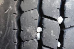 (SECTION 1: Irregular drive tire conditions) 4. Stone Retention/Drilling Appearance: Stones or gravel imbedded between tread blocks, sometimes reaching steel cables. Probable Cause: Condition is common with vehicles operating on gravel surfaces. Overinflation, misapplication of the tire. Corrective Action: Remove stones and return to service. Maintain proper inflation pressures. Tire Disposition: Continue to run unless there are multiple spots reaching steel cables. Consult retreader or tire manufacturer. (SECTION 1: Irregular drive tire conditions) 4. Stone Retention/Drilling Appearance: Stones or gravel imbedded between tread blocks, sometimes reaching steel cables. Probable Cause: Condition is common with vehicles operating on gravel surfaces. Overinflation, misapplication of the tire. Corrective Action: Remove stones and return to service. Maintain proper inflation pressures. Tire Disposition: Continue to run unless there are multiple spots reaching steel cables. Consult retreader or tire manufacturer.