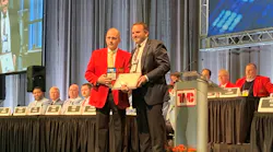 Kenneth Calhoun presents the Silver Spark Plug award to Peter Savage, director of quality and implementations at Clarke Power Services during the TMC Fleet Operator's Forum.