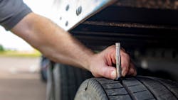 A proper pre-trip inspection involves drivers checking tire pressure before they hit the road.