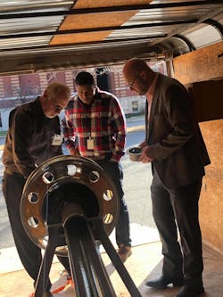 Bill Turner (left) demonstrates how the TetherTech device attaches to the wheel end. The system prevent wheel-off events even in the absence of traditional hub fasteners.