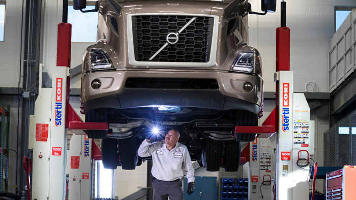 A technician inspects the underbody of a vehicle using a four-post lift, a key component to shop safety.