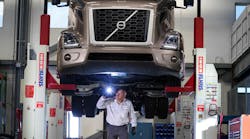 A technician inspects the underbody of a vehicle using a four-post lift, a key component to shop safety.
