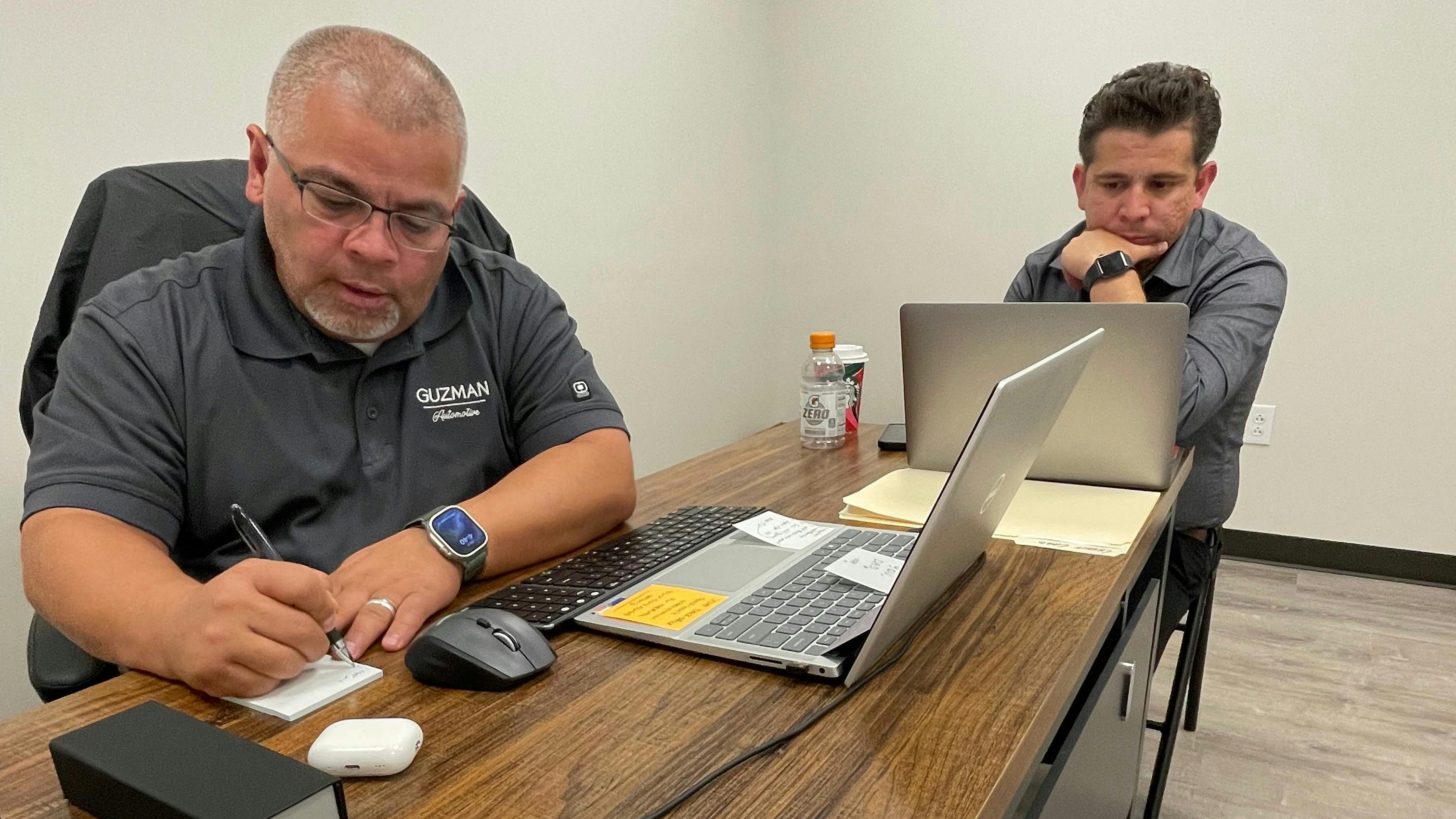 James Guzman (left) and his son Joe Gonzales (right) going over the books at the shop they co-own, Guzman Automotive.