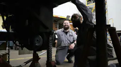 Transport Services technical advisor Mike Conley shows apprentice Dylan Greve how to work on a trailer wheel end.