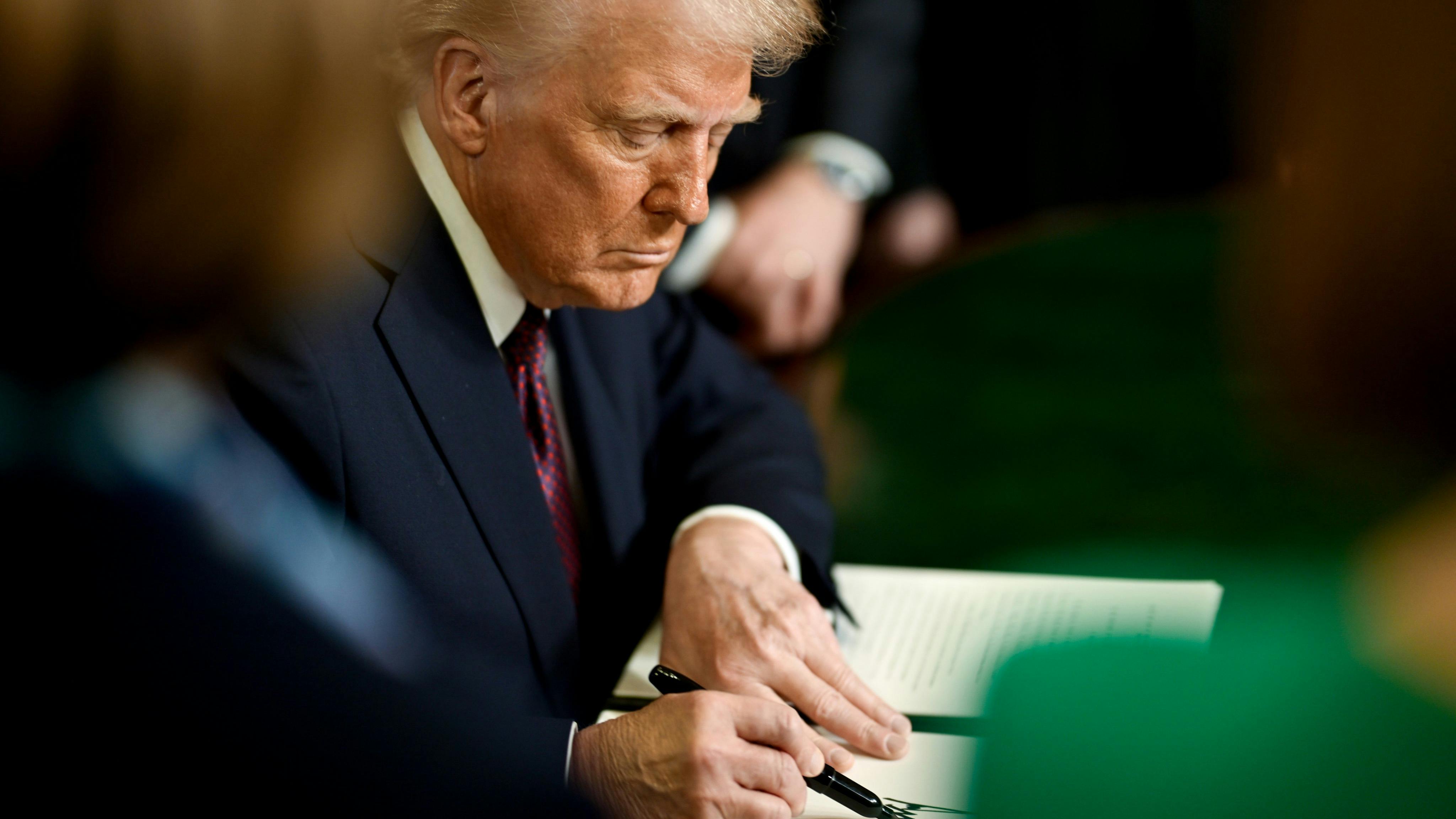 President Donald Trump signs an executive order on the first day of his second term in office.