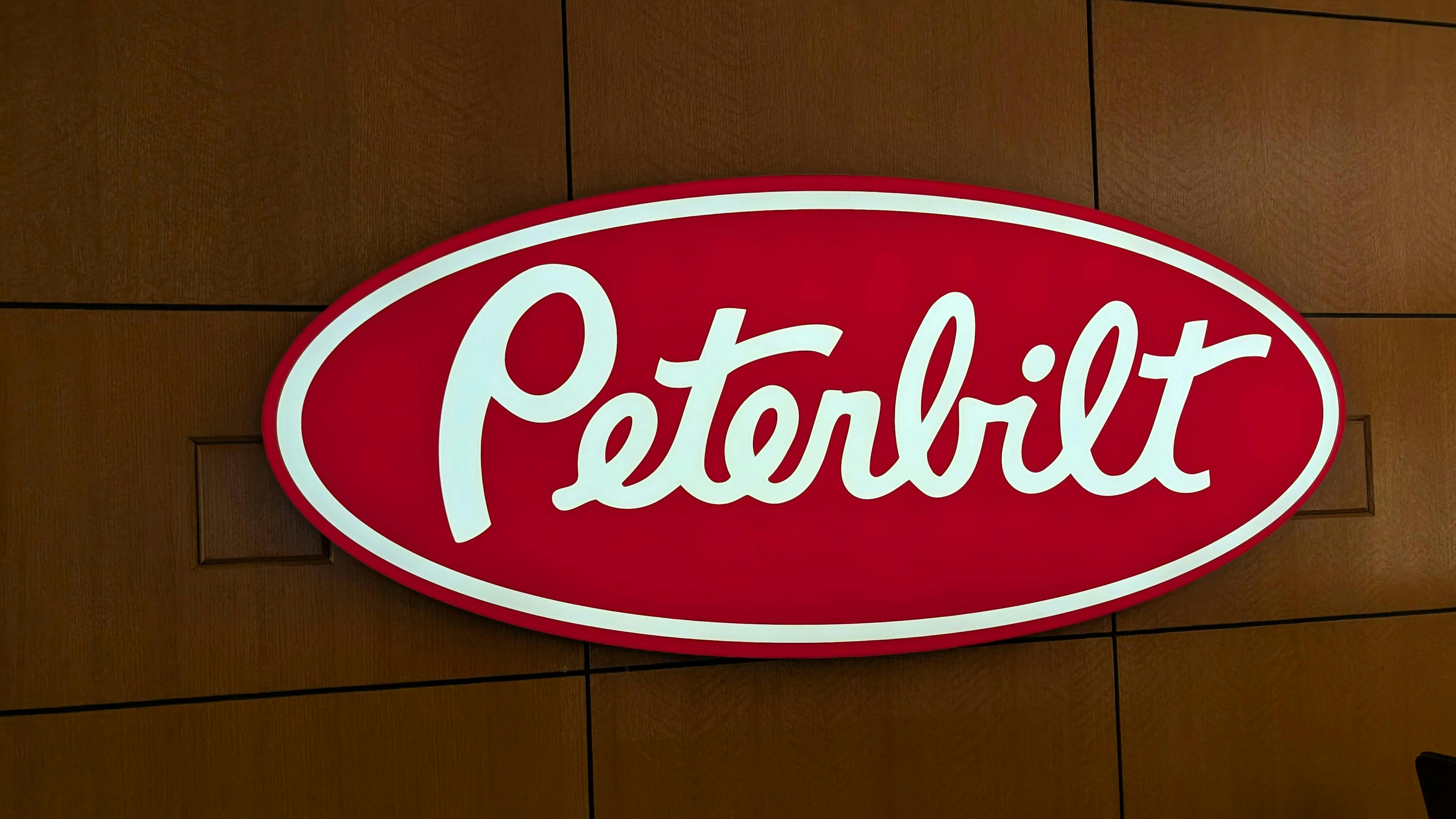The iconic Peterbilt red oval logo on display in the OEM's Denton, Texas, corporate headquarters.