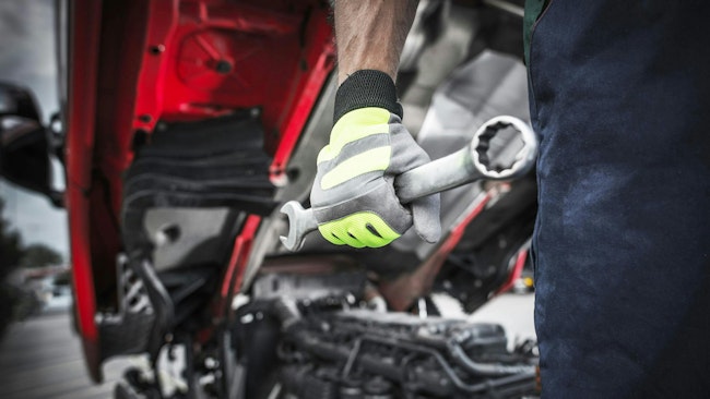 Technician with wrench in front of truck